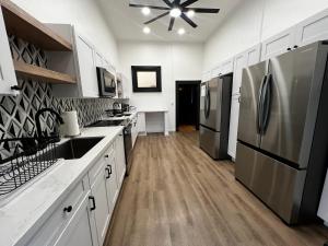 希洛Howzit Hostels Hawaii的厨房配有白色橱柜和不锈钢冰箱