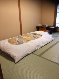 奈良Ryokan Kosen Kazeya Group的一张床上床,床上有毯子,铺在地板上