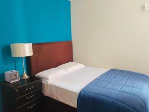 特鲁希略Exclusivo Apartamento en el Centro de Trujillo的一间卧室配有一张床和一个带灯的床头柜