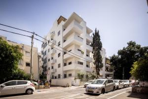 特拉维夫Heart of Tel Aviv Garden Oasis by Sea N' Rent的白色的建筑,有汽车停在停车场