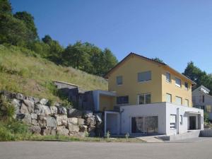 SteinachRebenrain Comfortable holiday residence的一座黄色和白色的建筑,靠近石墙