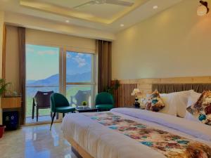 穆索里The Pine Woods - A Four Star Luxury Resort in Mussoorie的酒店客房设有一张床和一个大窗户