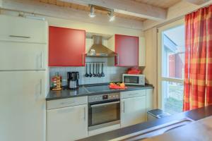 巴贝Ferienhaus Seepferdchen的厨房配有红色橱柜和炉灶烤箱
