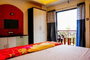 潘奇加尼HOTEL SAMRUDDHI的一间卧室设有一张床、一台电视和一个窗口。