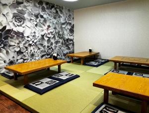 大岛三浜館 伊豆大島的一间设有三张桌子的房间和一堵鲜花的墙壁