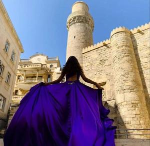 巴库Eminera Hostels Baku的站在城堡前身穿紫色衣服的女人