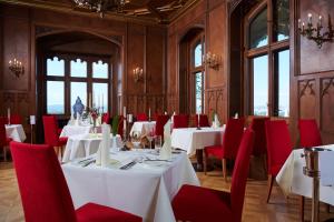 德累斯顿艾克城堡酒店的用餐室配有白色的桌子和红色的椅子