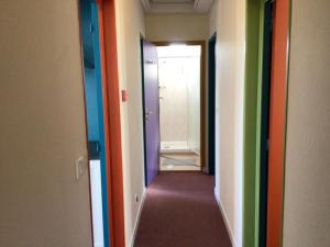巴尼奥勒德日洛恩Hôtel Bellevue Bagnoles Normandie的走廊上设有不同的彩色门,走廊上设有走廊
