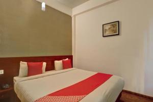 乌提Flagship Ooty Residency的一间卧室配有一张带红色枕头的大床
