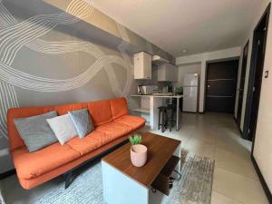 危地马拉Nice Apartment in Zone 4的客厅里一张橙色的沙发,配有桌子