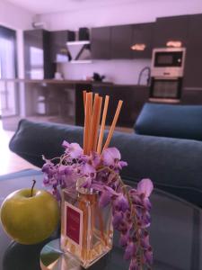 GhirodaAURORA suites的紫色花瓶和桌子上的苹果