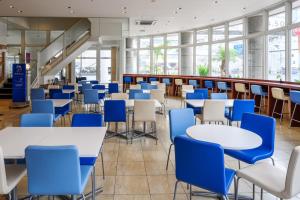 那霸东横INN 冲绳那霸旭桥站前的一间设有桌子和蓝色椅子的自助餐厅