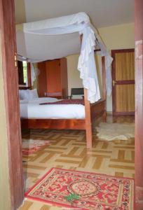 Sekenanisunshine maasai Mara safari camp in Kenya的一间卧室配有一张天蓬床和地毯。