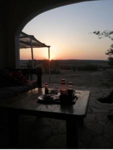 Sekenanisunshine maasai Mara safari camp in Kenya的一张桌子,上面有饮料,背面有日落