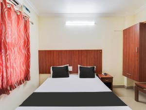 钦奈OYO Meenaachi Inn的卧室配有白色的床和木制床头板