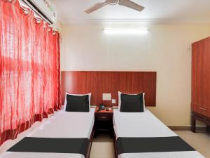 钦奈OYO Meenaachi Inn的配有红色窗帘的客房内的两张床