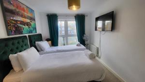 伦敦Garland Central City Apartment London 2的一间卧室设有两张床、一台电视和一扇窗户。