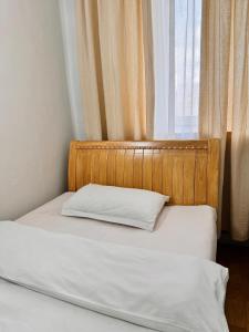 乌兰巴托Khongor Guest house & Tours的靠窗的一张带木制床头板的床