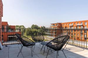 根特Spacious apartment with beautiful terrace near Ghent的阳台配有3把椅子和1张桌子