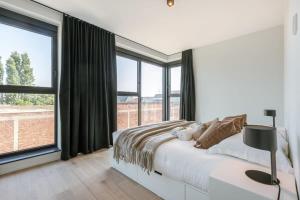 根特Spacious apartment with beautiful terrace near Ghent的白色卧室设有床和大窗户