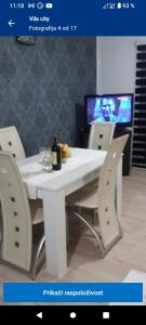 比耶利纳Vila City的一张带椅子的白色桌子和一瓶葡萄酒