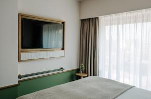 波兹南PURO Hotel Poznań Stare Miasto的一间卧室设有一张床、一台电视和一个窗口。
