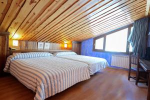 贝纳斯克HOTEL TURPÍ的一间卧室设有两张床和木制天花板