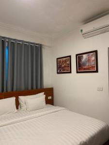 河内A25 Hotel - Đội Cấn 2的一间卧室设有两张带白色床单的床和窗户。