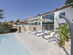 卡隆赫VILLA LA DOLÇA CALONGE的一个带白色椅子的游泳池以及一座房子