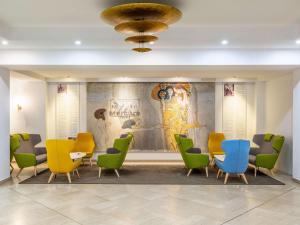 维也纳美居维也纳威斯特班霍夫酒店的一间设有五颜六色的桌椅和壁画的等候室