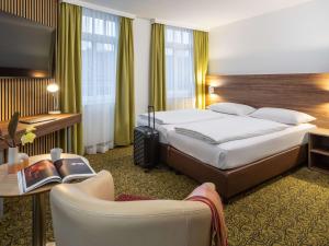 维也纳美居维也纳威斯特班霍夫酒店的酒店客房带一张大床和一把椅子