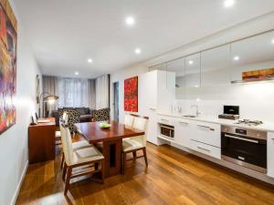 墨尔本The Sebel Residences Melbourne Docklands Serviced Apartments的厨房以及带木桌和椅子的用餐室。