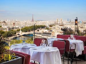 巴黎SO/ Paris Hotel的一间设有桌椅的餐厅,享有城市美景