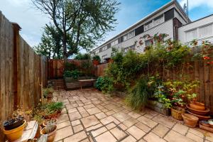 伦敦3bed house with patio & parking - 9 min to Station的种有盆栽植物和木栅栏的花园