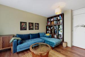 伦敦3bed house with patio & parking - 9 min to Station的客厅设有蓝色的沙发和书架