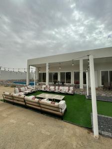 Al RahbaRashed Farm的一座带椅子和绿色草坪的大型建筑
