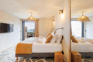 耶尔Le Domaine de la mer - Beach hotel Nature&Authenticité Hyères的配有电视和窗户的客房内的两张床