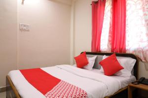 DhantoliOYO Prithvi Inn的一间卧室配有红色和白色枕头的床