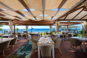 法里拉基罗德斯帕拉蒂姆休闲及健康酒店的餐厅设有桌椅,背景为大海