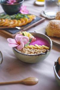 吉利阿尔Sunny Rose Bungalows Gili Air的桌上一碗带粉红色花的食品