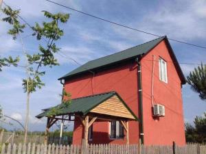 乌雷基Natali & Giga的一道红色房子,在栅栏后面有绿色屋顶
