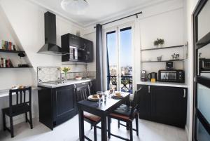 巴黎GuestReady - Cozy and Bright with Notre Dame View的厨房配有黑色橱柜和桌椅