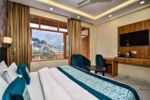 麦罗肯机Hotel Pawan Regency Mcleodganj的配有一张床、一张书桌和一扇窗户的酒店客房