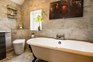 SaughallSpacious & well decorated 4 bedroom home near Chester的浴室设有白色浴缸和墙上的绘画作品