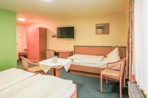 吕贝克理想酒店的客房设有两张床、一张桌子和一台电视机。
