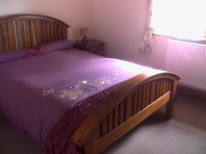 兰卡斯特Knotts Farm Holiday Cottages的一间卧室配有一张带紫色棉被的木床