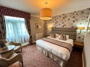 凯西克Lodore Falls Hotel & Spa的配有一张床和一把椅子的酒店客房