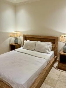 乌布蜜月旅馆的一间卧室配有一张床,两台桌子上放着两盏灯