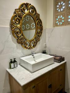 乌布蜜月旅馆的浴室设有白色水槽和金色镜子