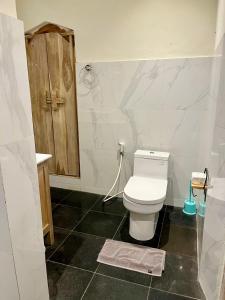 乌布蜜月旅馆的浴室配有白色卫生间和盥洗盆。